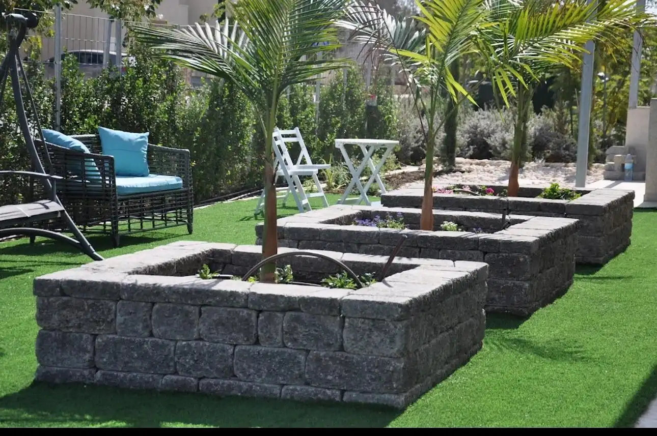 Raised planters with palms set into a lawn.