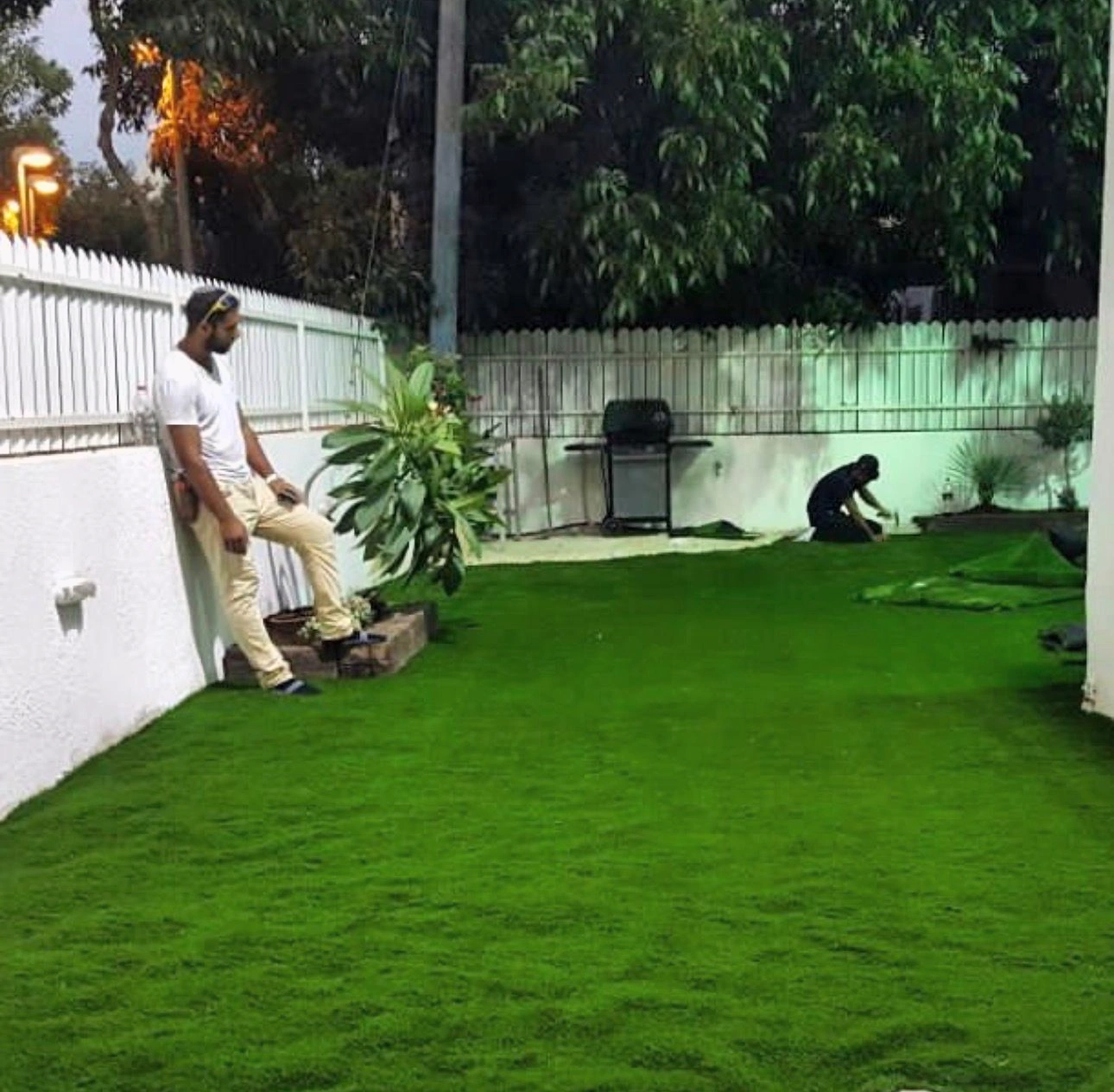 Artificial turf being fitted across a courtyard.
