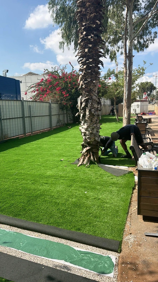 Artificial turf fitted around the base of a palm.