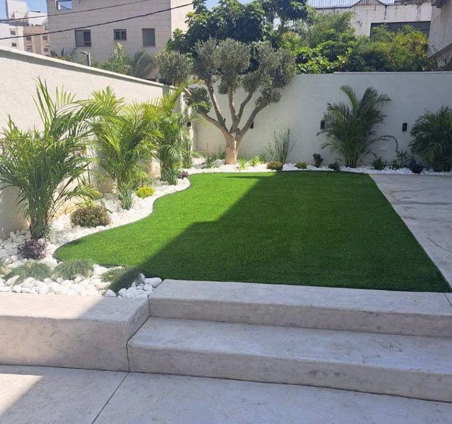 Artificial turf in a courtyard, with planting along the walls and an open center.