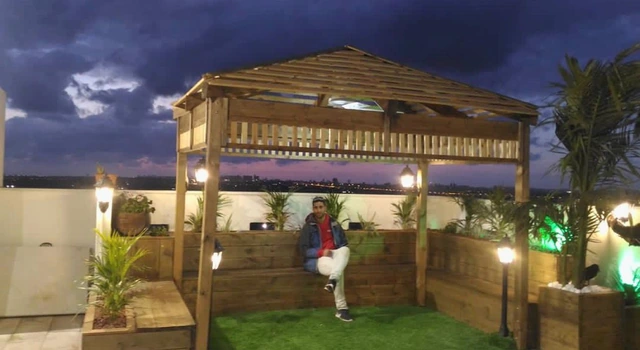 Rooftop garden with a wood gazebo and a seating area with plants.